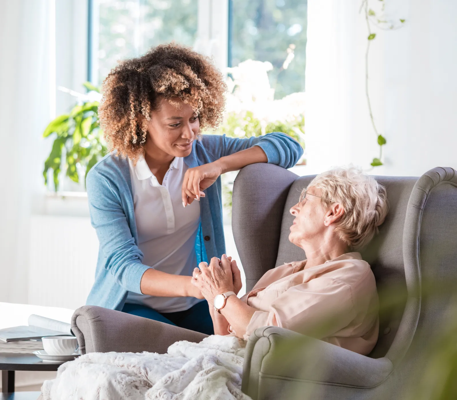 Caregiver talking with elderly woman in chair
