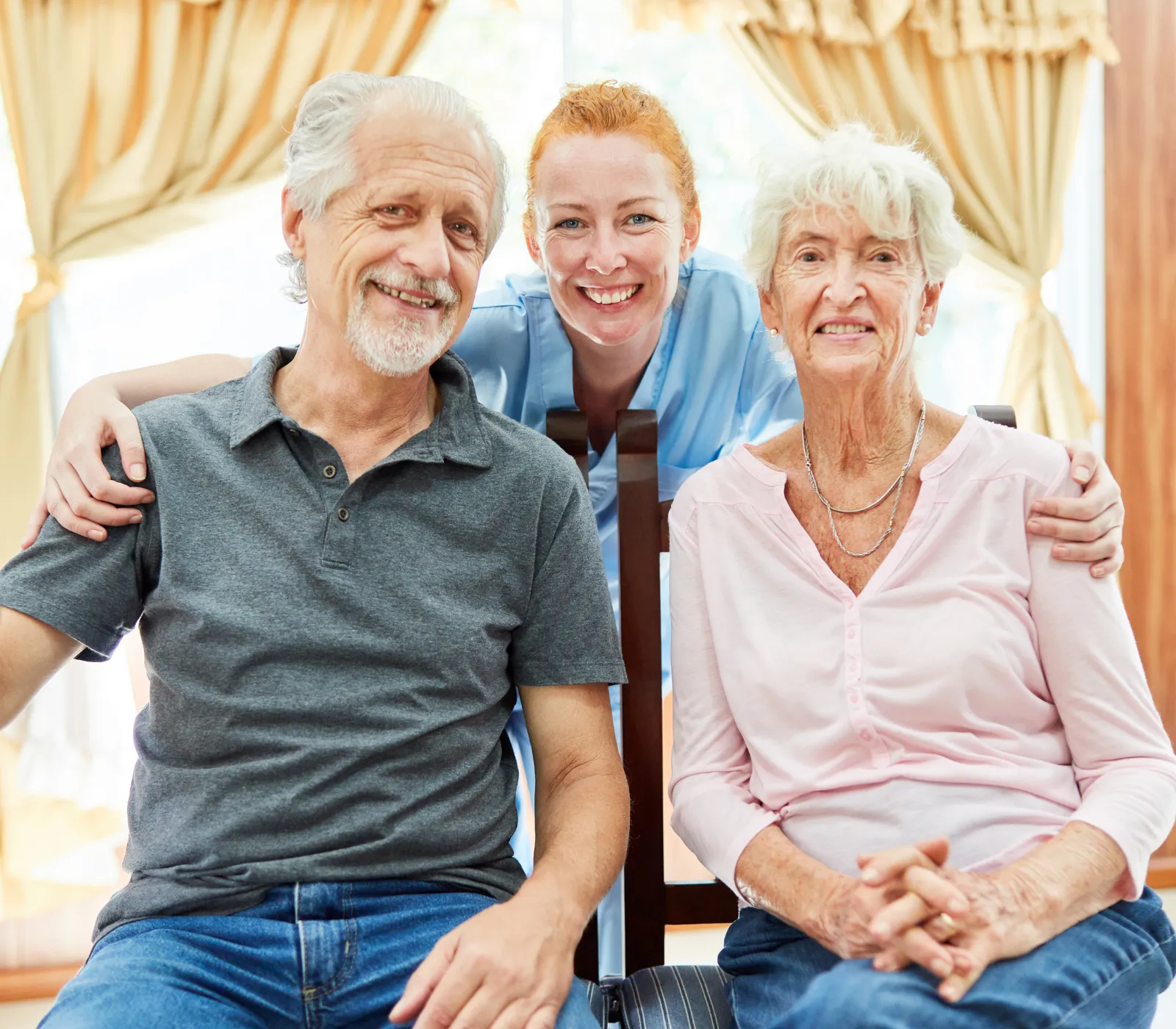 Caregiver smiling with elderly couple at home