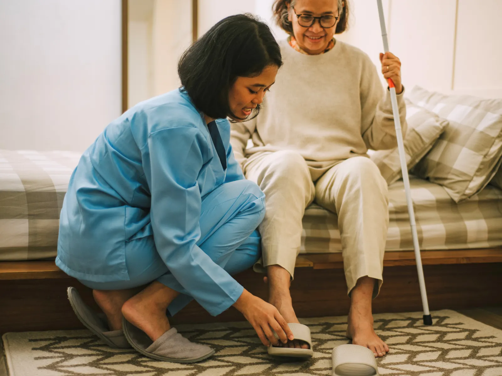 Caregiver helping elderly woman put on slippers