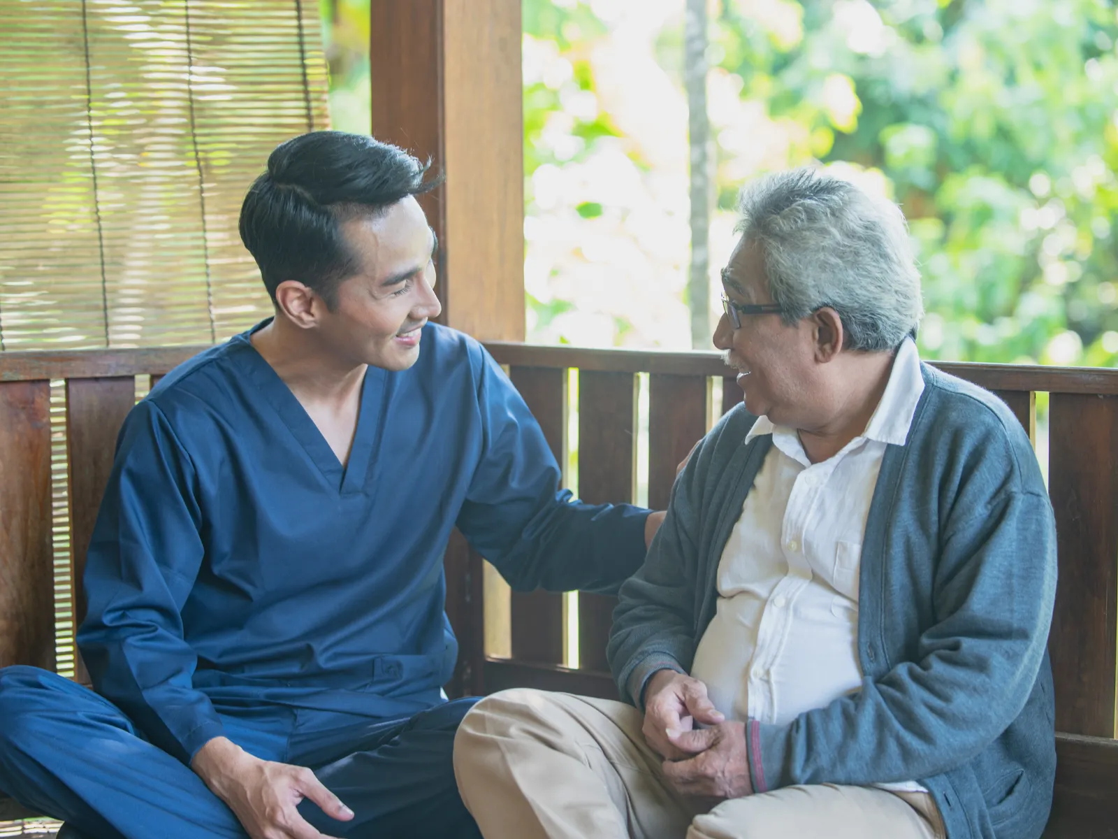 Caregiver chatting with elderly man on porch