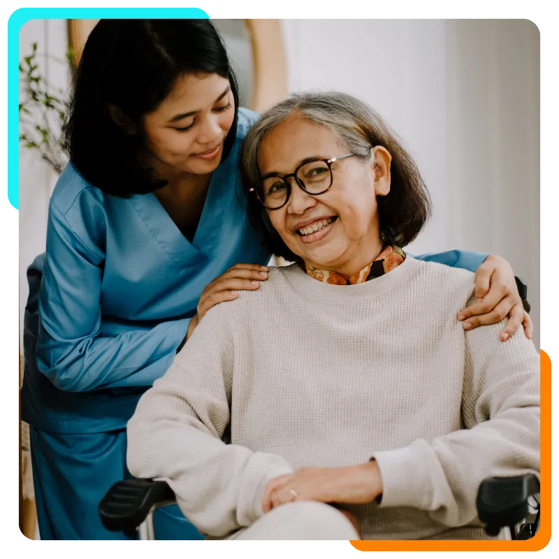 Caregiver and elderly woman smiling in wheelchair