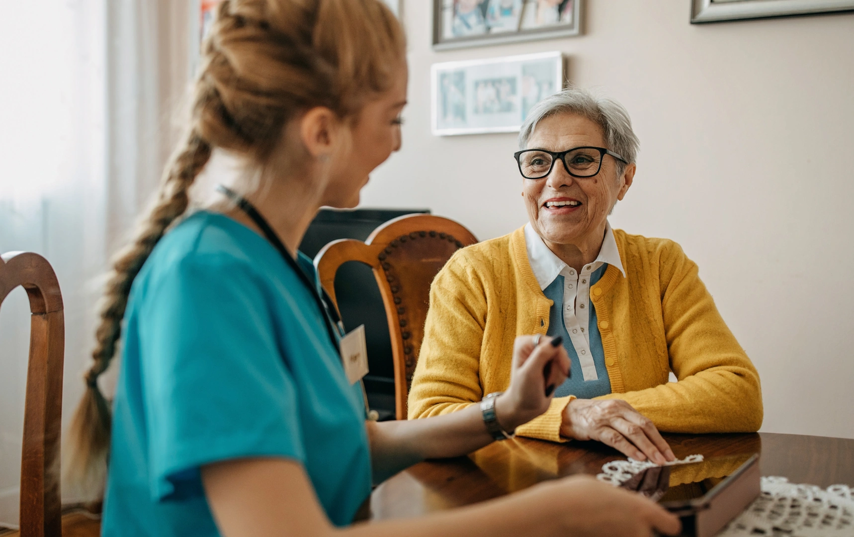 Caregiver with smiling senior woman at table
