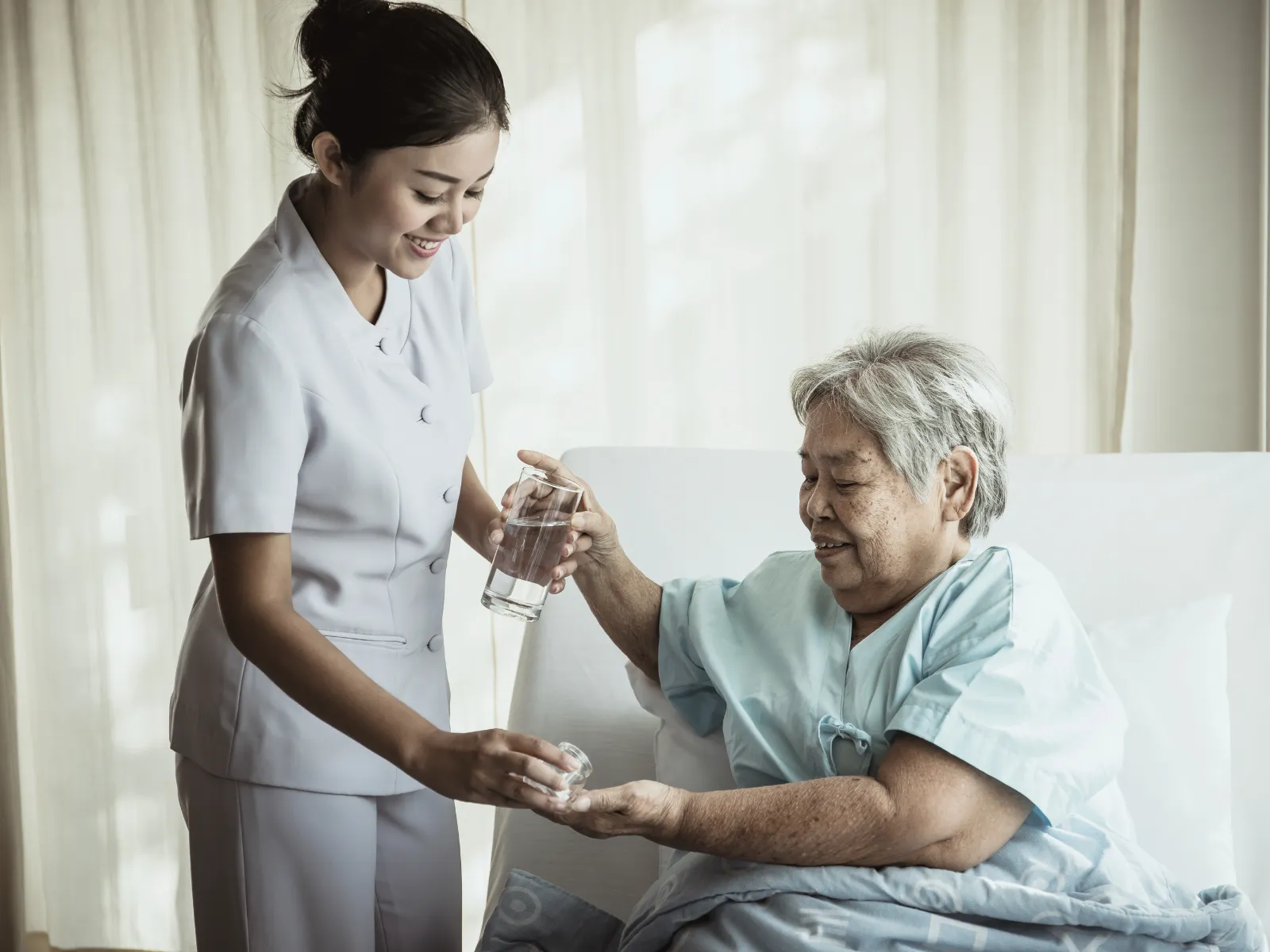 Nurse assisting elderly patient with medication