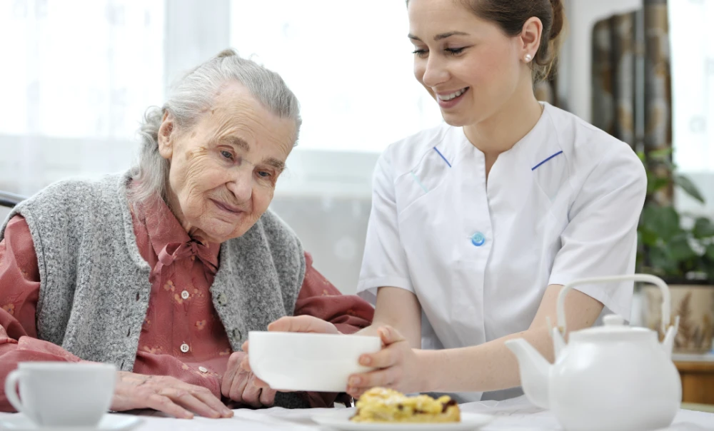Caregiver serving food to elderly woman