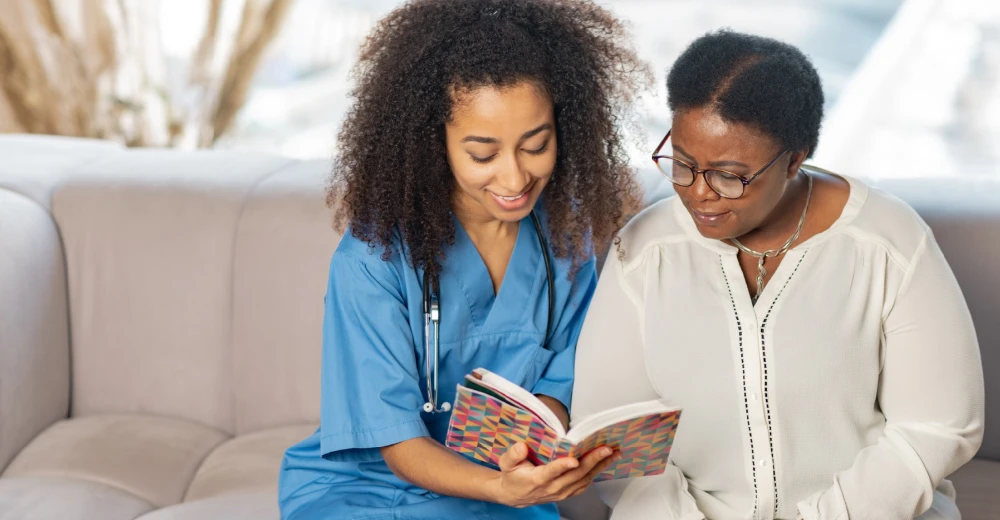 Nurse reading colorful book with older woman
