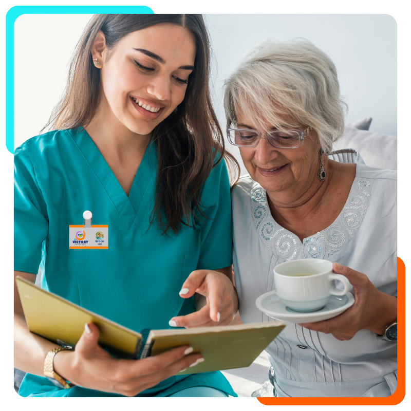 Caregiver reading to elderly woman holding teacup