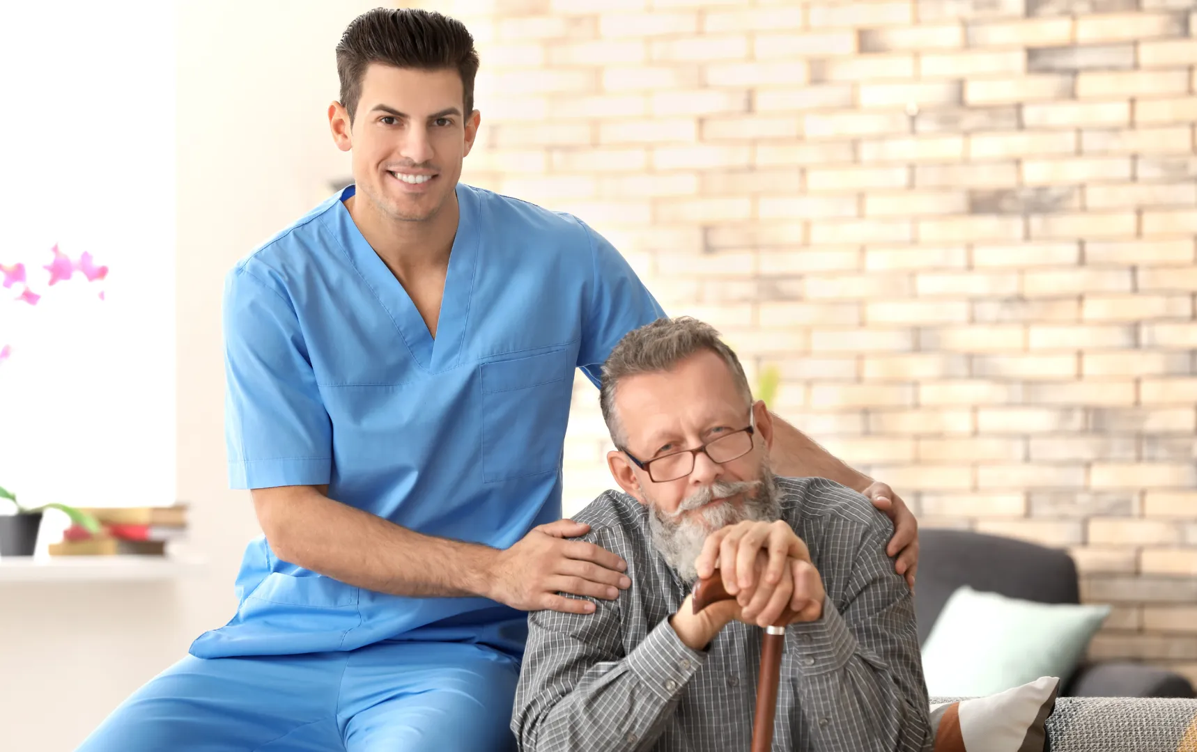 Caregiver in blue scrubs with elderly man