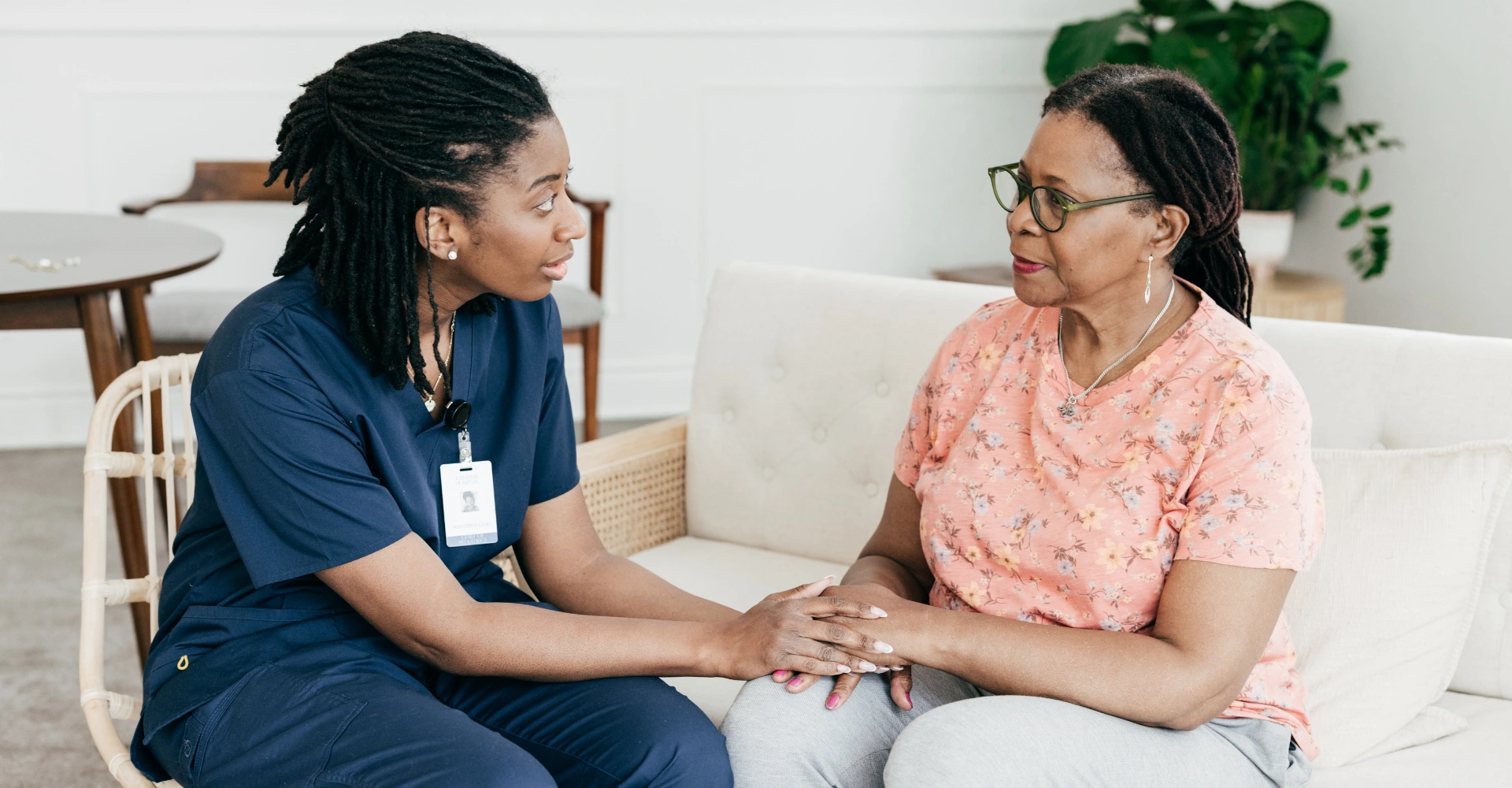 Nurse comforting older woman on couch