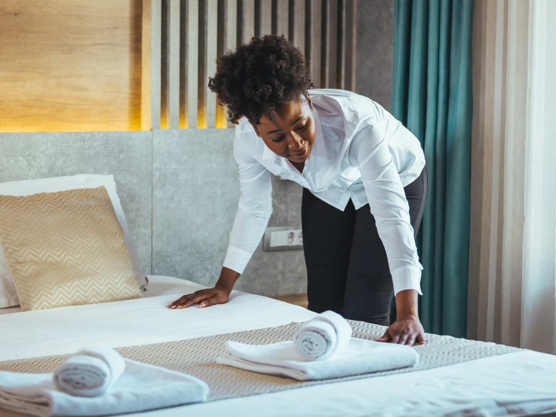 Hotel housekeeper arranging towels on bed