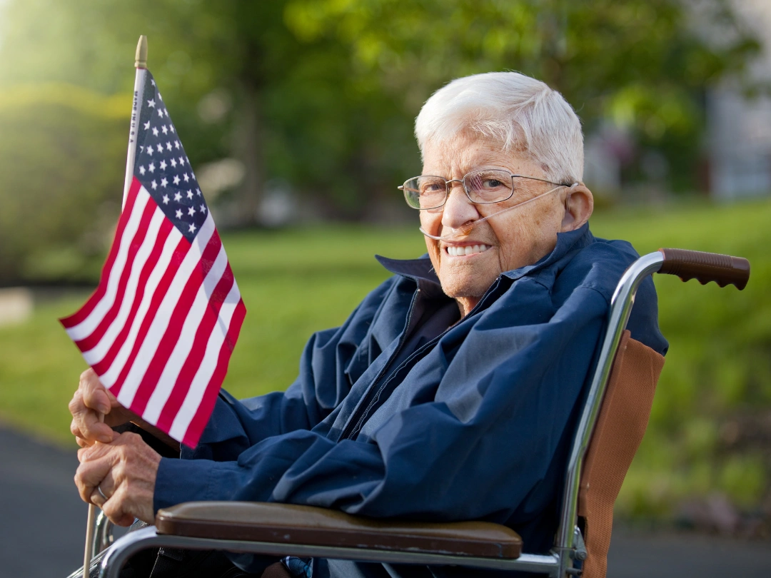 Elderly person smiling with American flag outdoors