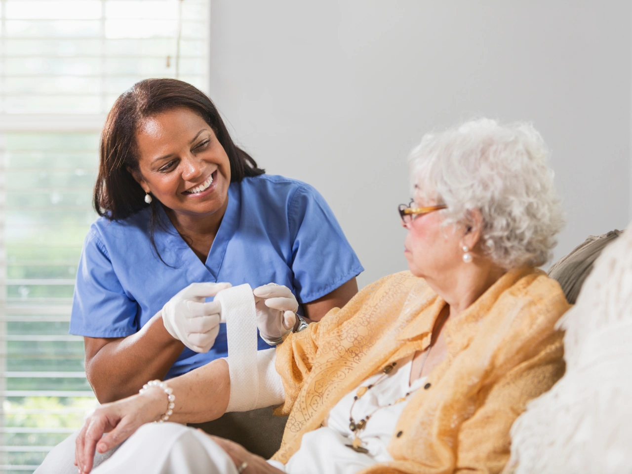 Nurse applying bandage to elderly woman