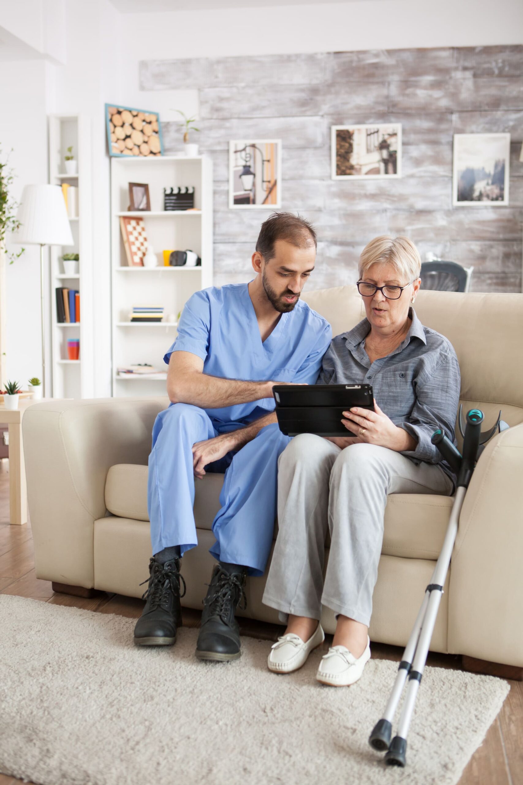 Caregiver showing tablet to elderly woman