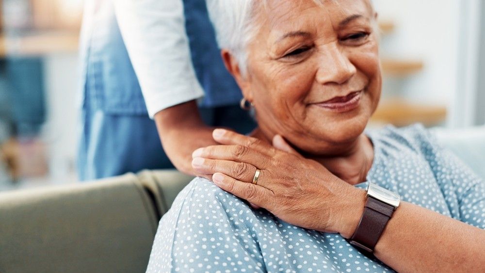 Senior woman comforted by caregiver's hands